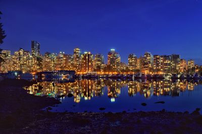 View of illuminated cityscape in front of calm lake at night