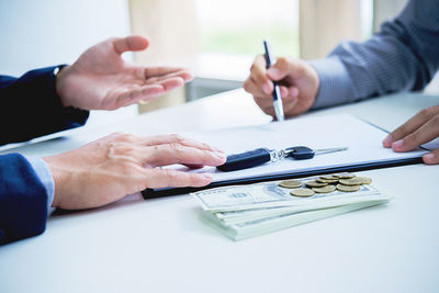 Midsection of businessman giving paper to customer in office