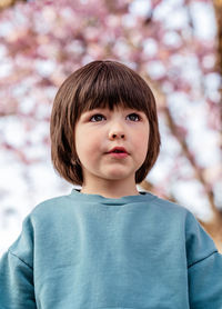 Outdoor portrait of cute little toddler boy in spring blooming garden