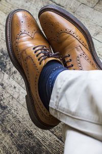 Low section of man wearing dress shoes on wooden floor