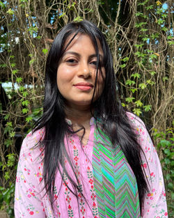 Portrait of young woman standing against plants