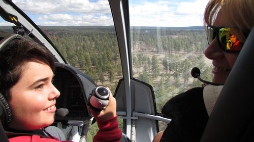 Rear view of happy woman and boy in helicopter over landscape