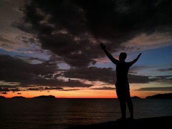 Silhouette man standing by sea against sky during sunset