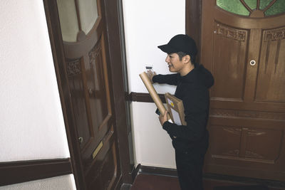 High angle view of smiling delivery man with package at doorstep