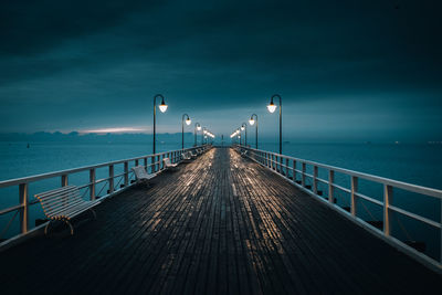 Empty pier over sea against sky