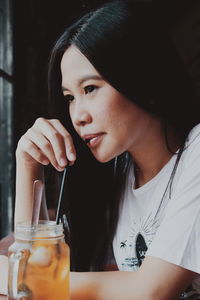 Close-up portrait of a young woman drinking glass