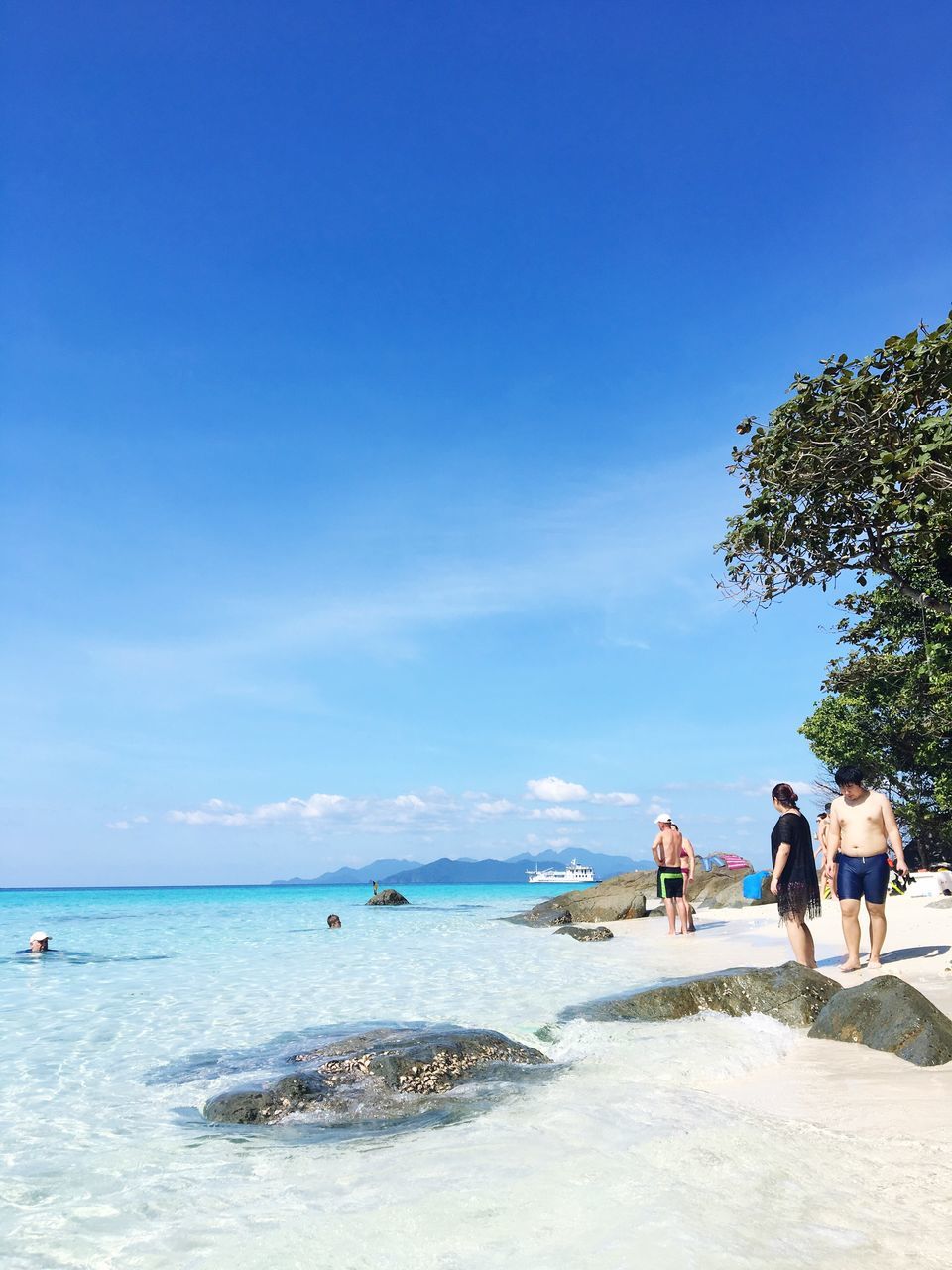 sea, beach, water, sky, blue, real people, nature, beauty in nature, horizon over water, scenics, relaxation, tourist, outdoors, tree, vacations, tranquil scene, large group of people, tranquility, palm tree, day, cloud - sky, men, people, adults only, adult