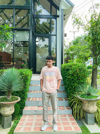 Portrait of young woman standing by plants