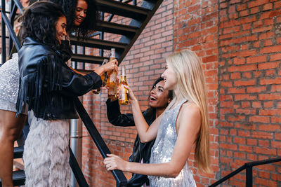 Friends toasting drinks while standing on staircase