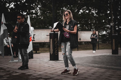 Full length of friends standing on footpath