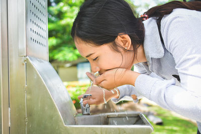 Close-up side view of young woman drinking water