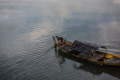 High angle view of young man standing in boat on lake