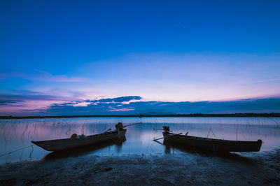 Boat moored in sea against sky during sunset