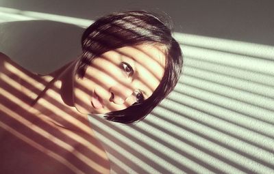 Close-up of young woman looking away while standing by wall