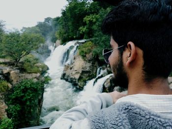 Close-up of young man looking at waterfall