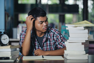 Side view of a young man sitting on table