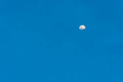 Low angle view of moon against clear blue sky