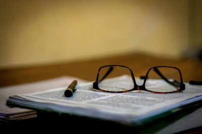 Close-up of pen and eyeglasses on book