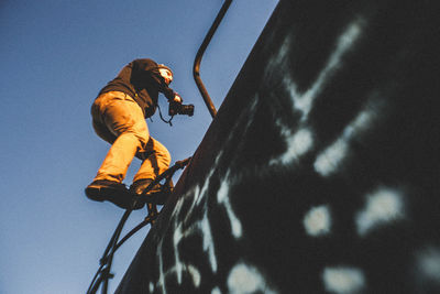 Low angle view of man climbing train car with camera