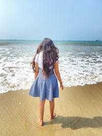 Rear view of woman on beach against sky