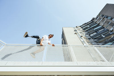 Young man with leg prosthesis performing parkour in the city