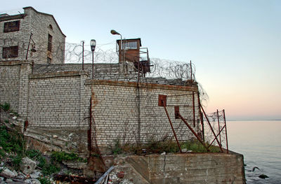 Abandoned building by sea against clear sky