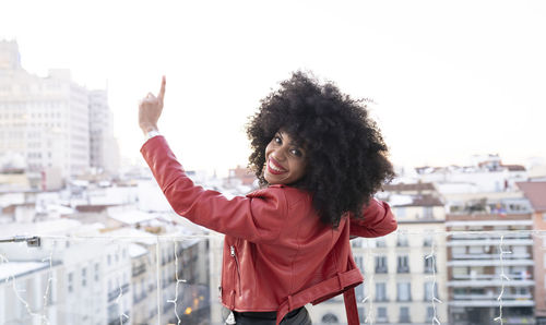 Portrait of smiling young woman standing against cityscape