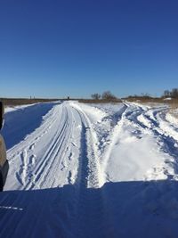 Snow covered landscape against clear blue sky