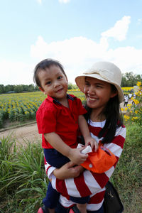 Mother carrying son on field