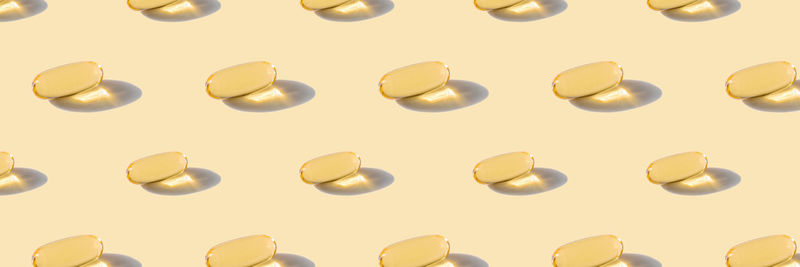 A pattern of omega capsules on a beige background.