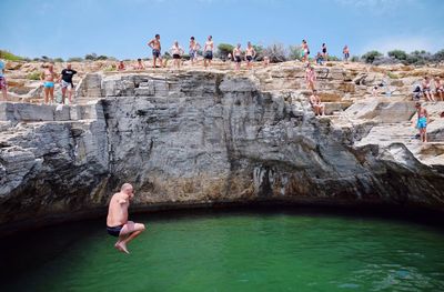 Group of people on rock formation in water