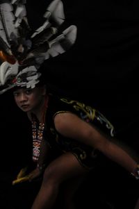 Midsection of woman dancing against black background