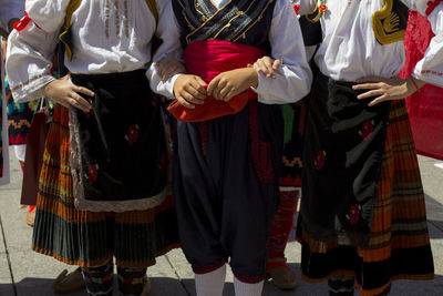 Midsection of people in traditional clothing dancing on street in city