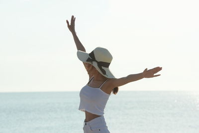 Smiling young woman at beach against sky