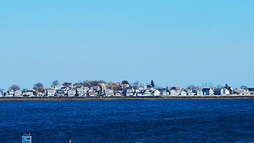 People on beach against clear blue sky