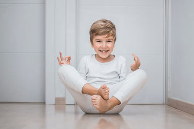 Portrait of smiling boy practicing yoga on floor
