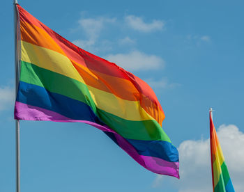 Low angle view of rainbow flags against sky