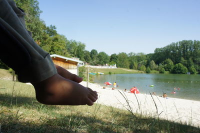 Rear view of man on swan by lake against sky