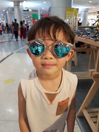 Portrait of cute boy wearing sunglasses while standing in shopping mall