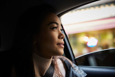 Thoughtful young woman looking through window while sitting in car