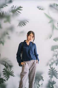 Young woman standing against trees