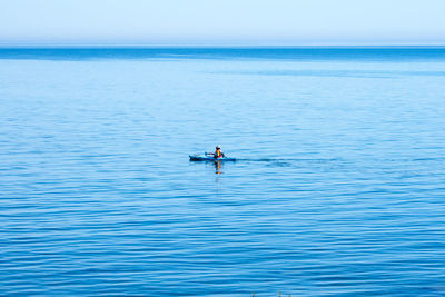 People sitting in sea against clear sky