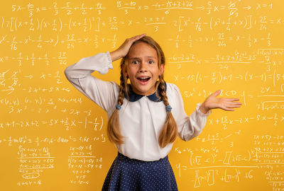 Portrait of surprised girl against mathematics on wall