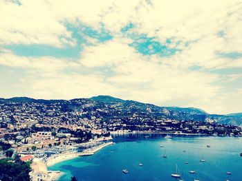 Aerial view of city by sea against sky