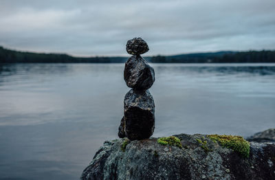 Close-up of statue on rock by lake against sky