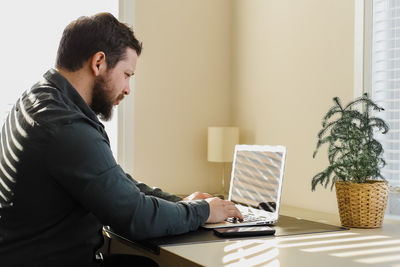 Side view of businessman using laptop at home