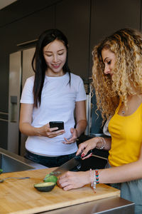 Young woman using phone while standing on mirror