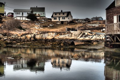 Houses by lake against buildings in city