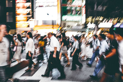 Blurred motion of people walking on road in city