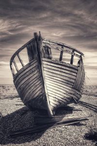 Old boat on beach against sky